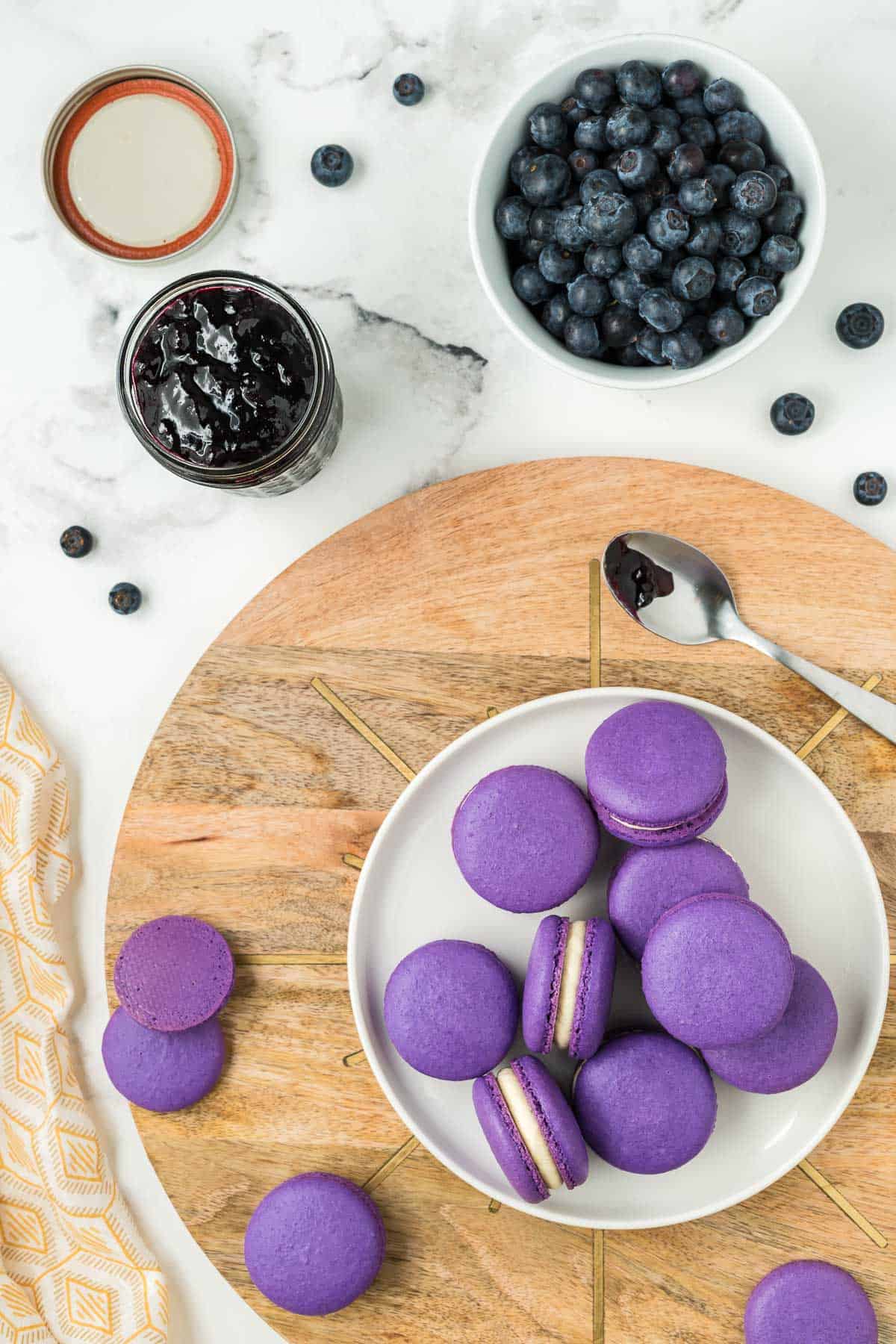 Blueberry macarons filled and matured and stacked on a white plate.