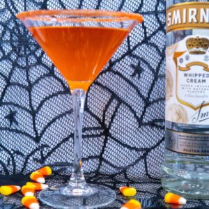 Halloween candy corn cocktail made with infused vodka with candy corn scattered around.