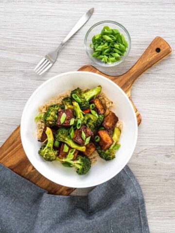 Vegan Mongolian tofu recipe in a white plate on a wooden serving board.