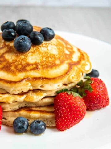 Pancake recipe with evaporated milk on a white plate with strawberries and blueberries.