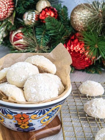 Snowball cookies in a bowl with Christmas decorations in the background.