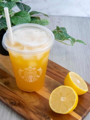 Starbucks peach green tea lemonade recipe in a Starbucks cup with lemons.