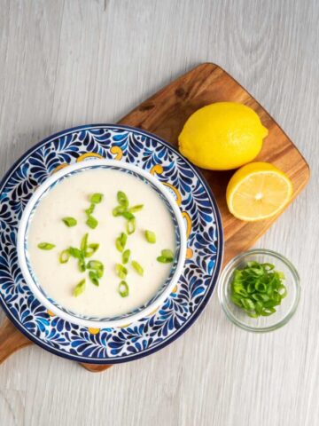 Tofu sour cream on a blue patterned plate with lemons and green onions.