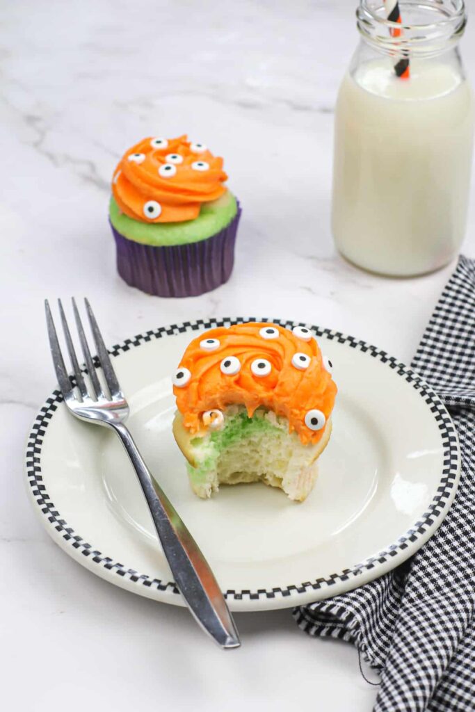 A monster eyeball cupcake on a plate with a fork.