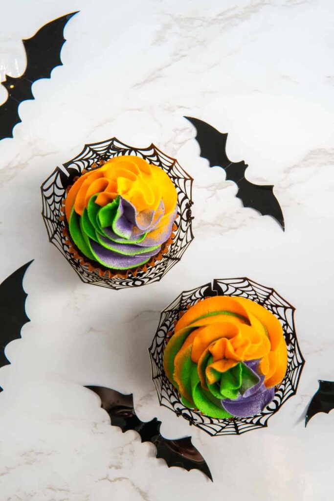 An overhead shot of Halloween cupcakes with decorative bats scattered around.