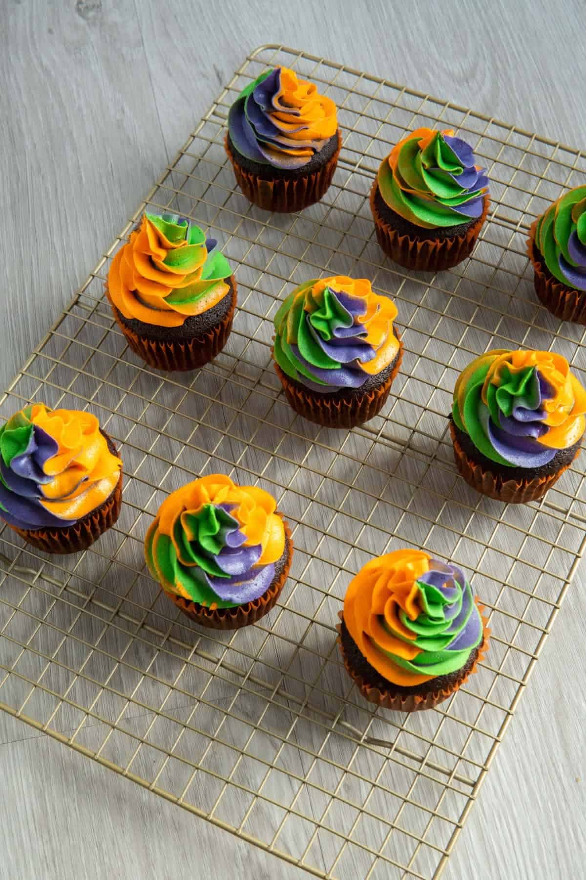 Halloween cupcakes topped with swirled orange, green, and purple frosting.
