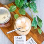 A copycat Starbucks iced chai tea latte on a wooden serving board with Tazo tea bags.
