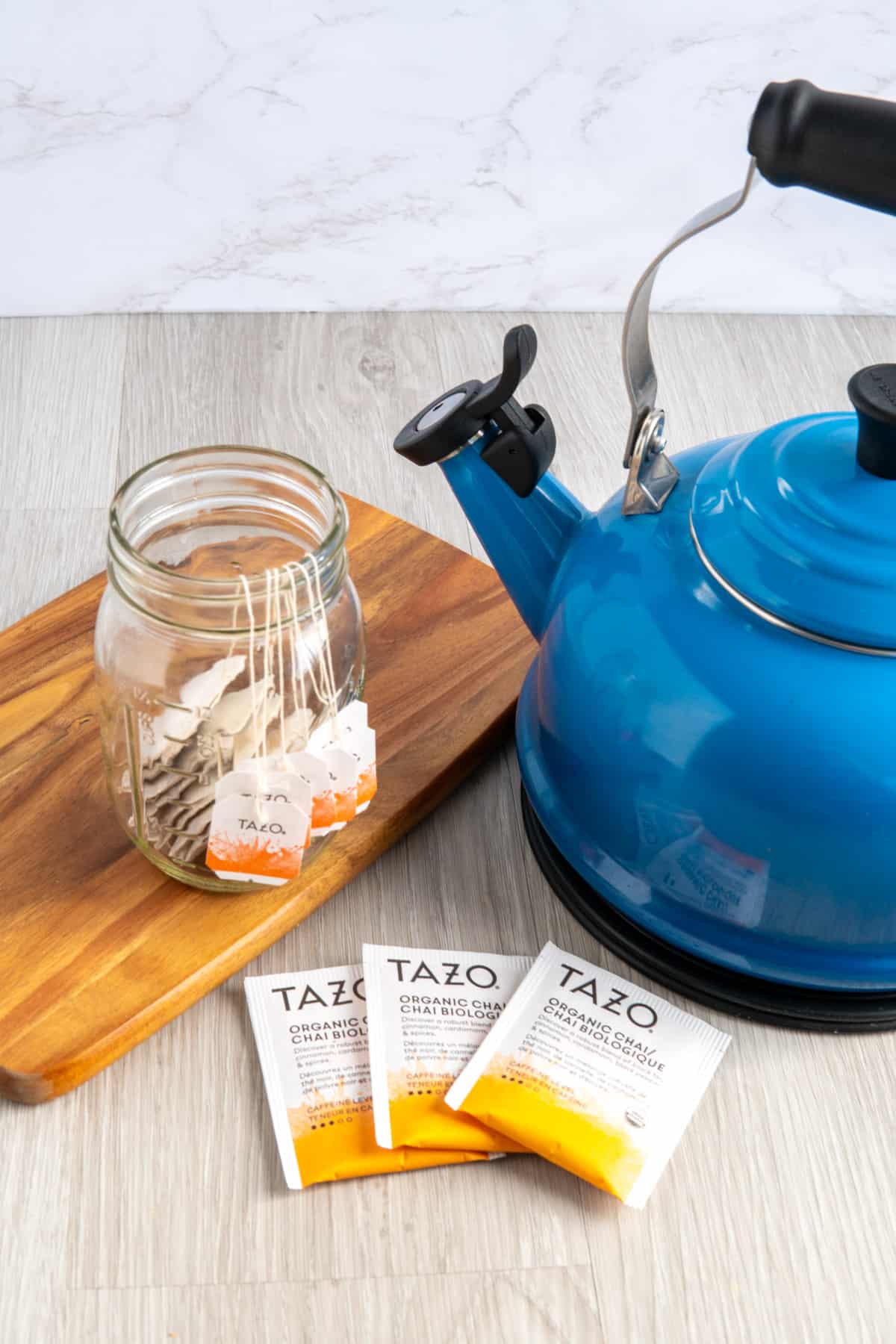 A jar with Tazo chai tea bags next to a blue Le Creuset kettle.