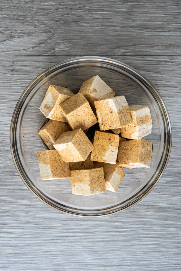 Tofu in a glass bowl with soy sauce marinade.