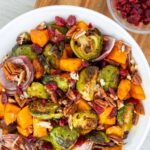 Roasted brussel sprouts sweet potatoes recipe on a wooden serving board.