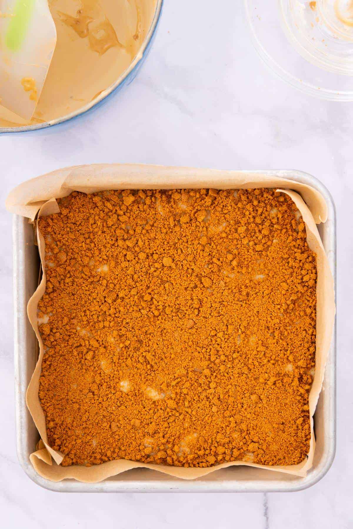 Biscoff fudge in a square pan topped with crushed biscoff cookie crumbs.