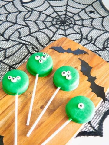 Halloween chocolate covered oreos on a wooden serving board with bats.