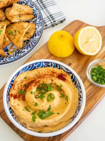 Hummus recipe without garlic in a blue patterned bowl with pita chips.