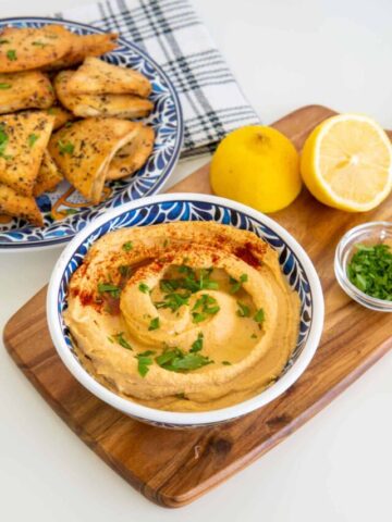 Hummus recipe without garlic in a blue patterned bowl with pita chips.