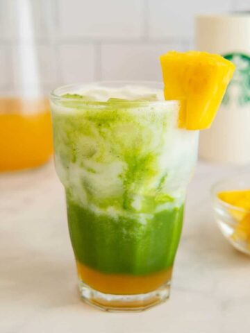 Unblended pineapple matcha drink in a glass with pineapple garnish.