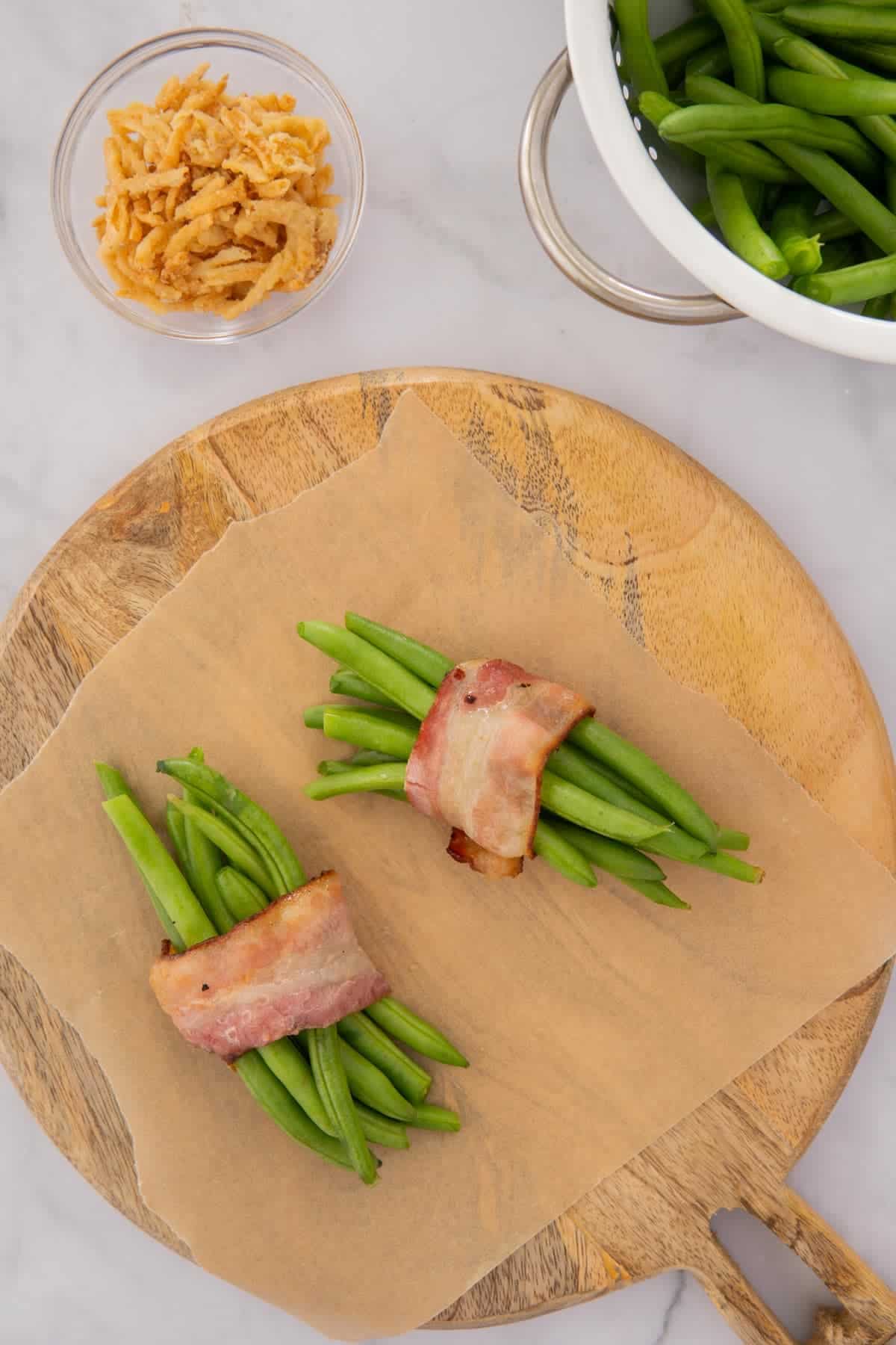 Green beans wrapped in bacon on a wooden board.