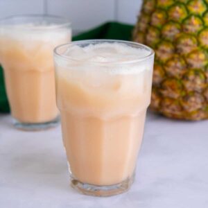Guava passion fruit Starbucks recipe drink in a glass in front of a pineapple.