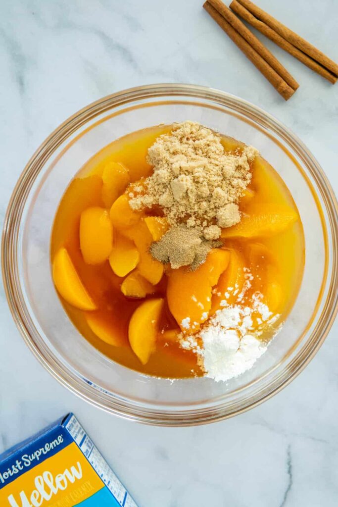 Peach cobbler ingredients in a glass bowl.