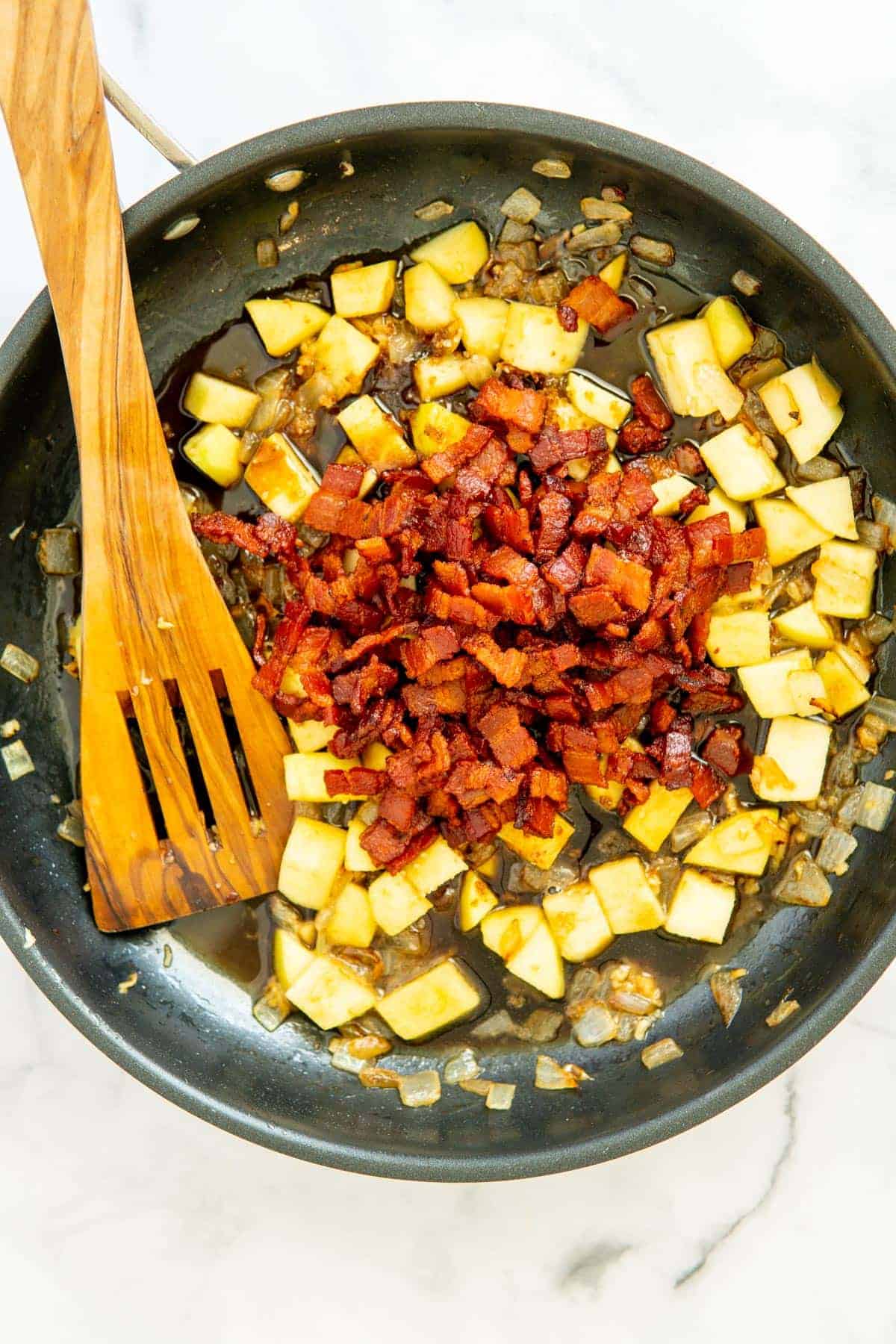 Apples and onions with bacon and remaining ingredients for jam in a frypan.