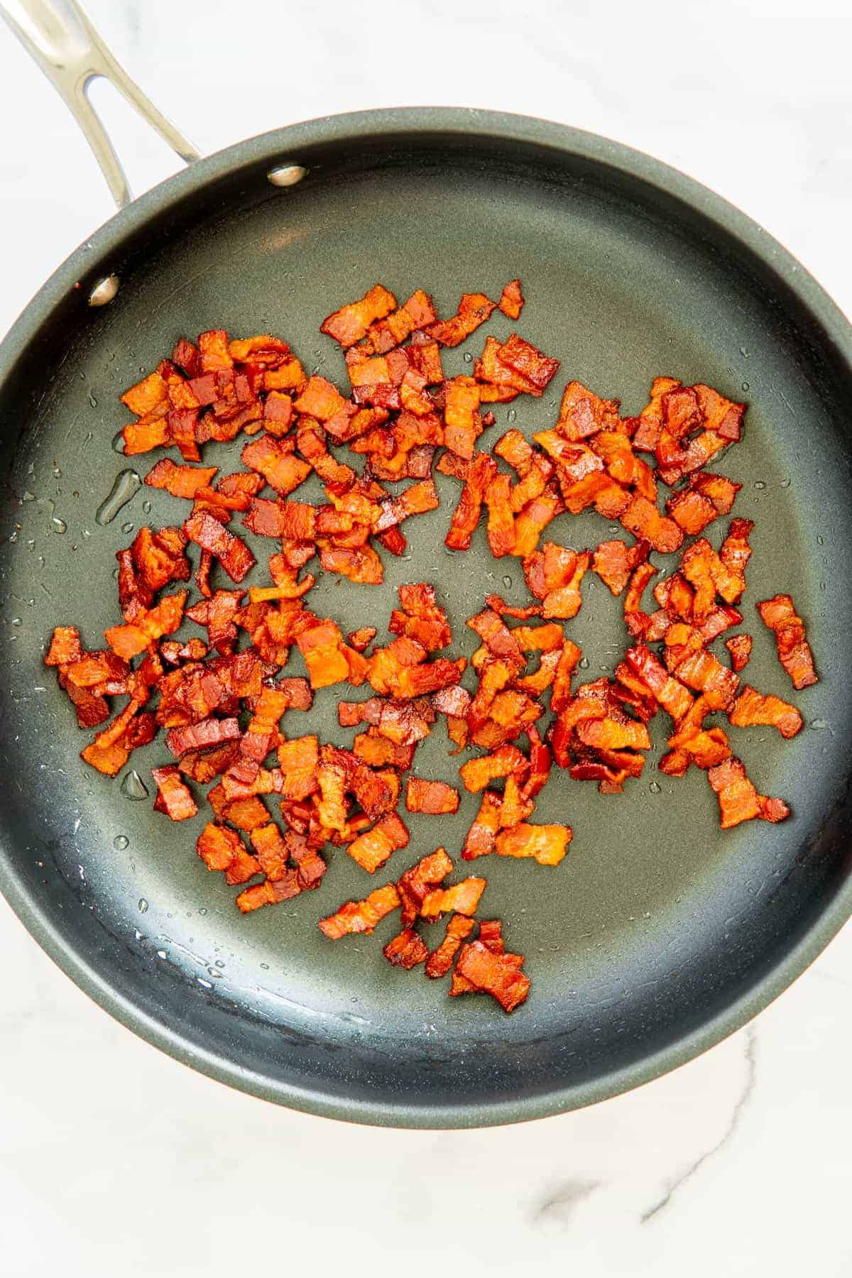 Drained cooked bacon in a frypan.