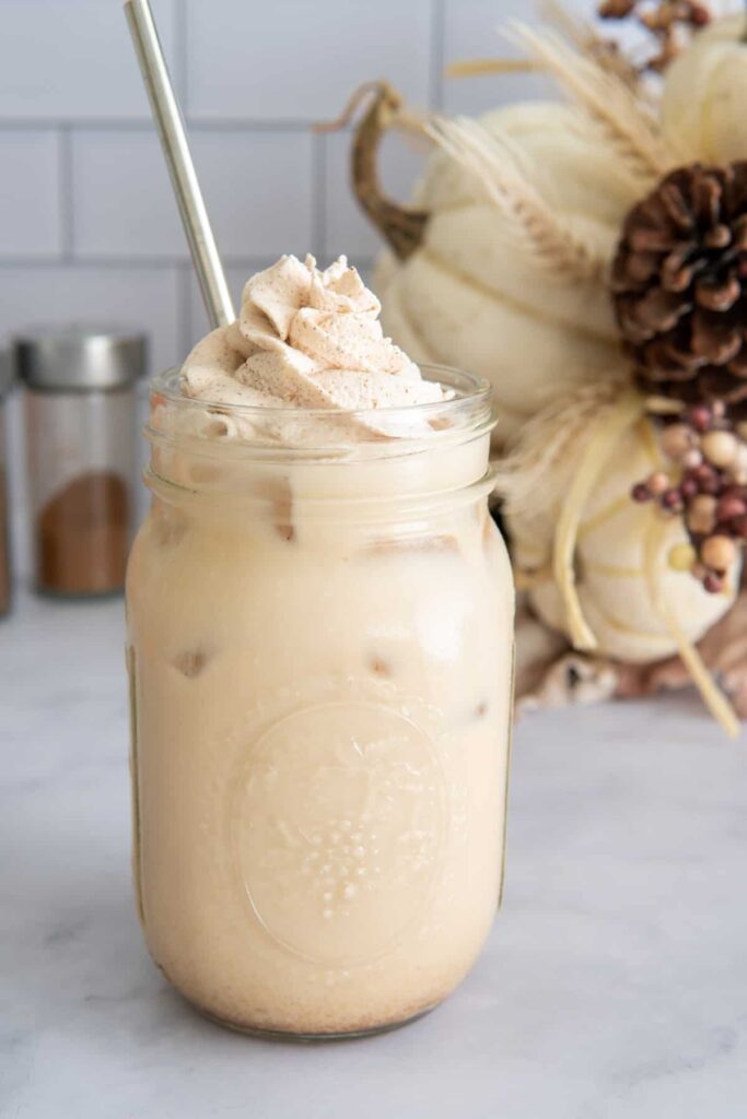 Pumpkin spice iced latte with whipped cream in a mason jar.