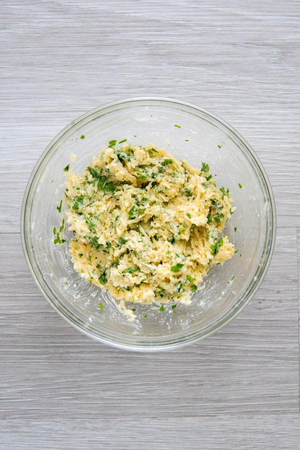 Garlic and parsley butter mixed in a glass bowl.