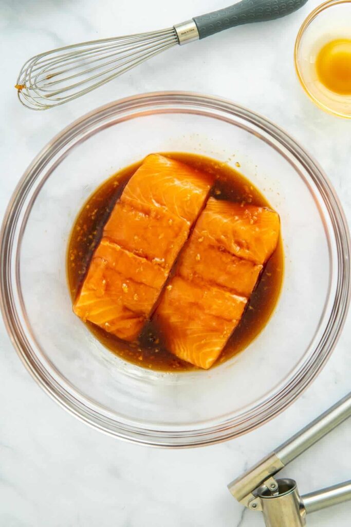 Salmon filets in teriyaki marinade in a glass bowl. 