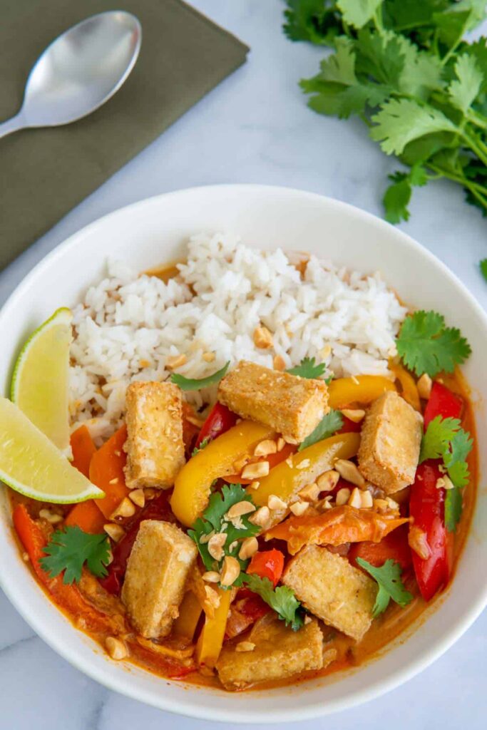 An overhead shot of vegan Thai red curry in a white bowl.