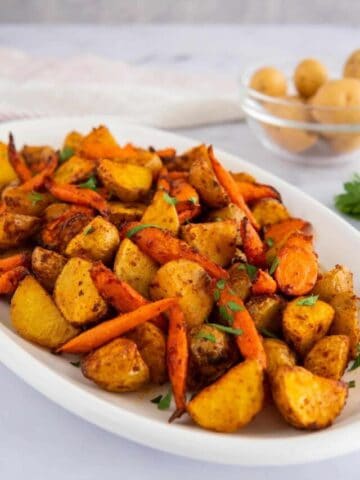Air fryer potatoes and carrots on a white platter.