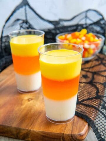 Candy corn jello shots with candy corn in the background.