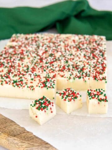 Three pieces of Christmas sugar cookie fudge cut away from the main block of fudge.