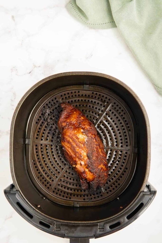 A cooked pork tenderloin in an air fryer basket.