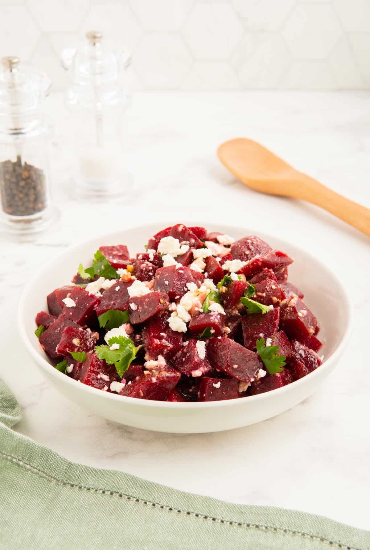 Beetroot and feta salad in a white bowl with a green napkin.