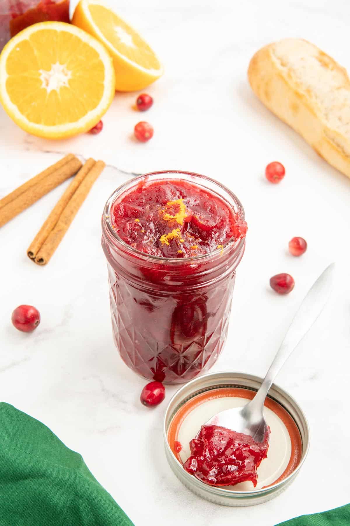 A spoonful of cranberry sauce with orange juice next to a jar of cranberry sauce.