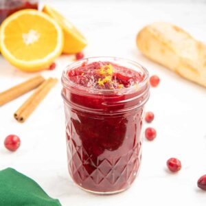 A glass jar containing cranberry sauce made with orange juice, cinnamon, and vanilla.