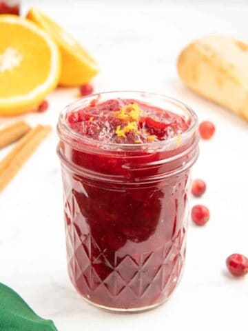 A glass jar containing cranberry sauce made with orange juice, cinnamon, and vanilla.