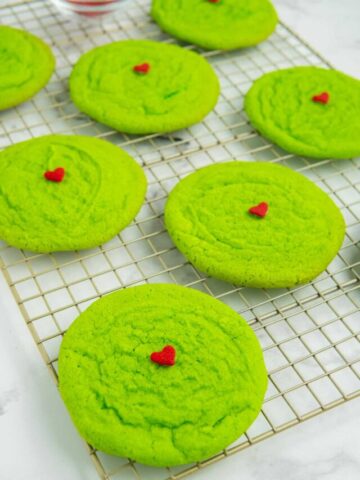 Decorated Grinch sugar cookies on a wire cooling rack.