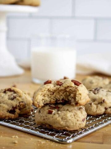 Maple pecan cookies stacked on a wire cooling rack with milk in the background.