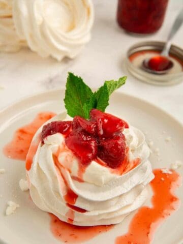 A close-up shot of a mini pavlova nest with strawberry compote.