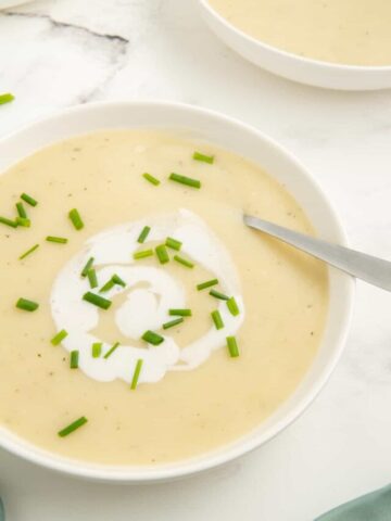 A close-up shot of potato and leek soup no cream with chives and coconut milk.