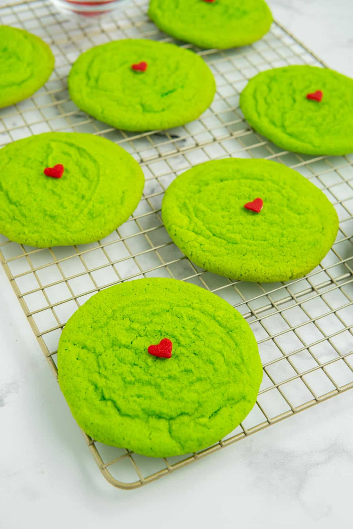 Decorated Grinch sugar cookies on a wire cooling rack.