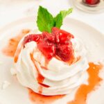 A mini pavlova nest topped with strawberry compote and mint.