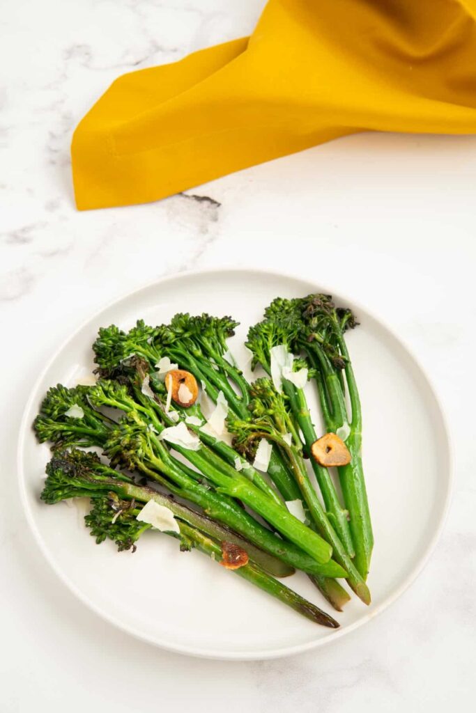 Pan-fried tenderstem broccoli on a white plate with a yellow napkin.