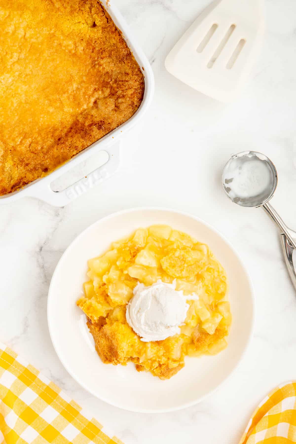 3 ingredient pineapple dump cake served in a white bowl with a scoop of icecream.