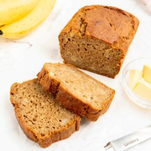 Two slices of 4 ingredient banana bread with butter in a glass dish.