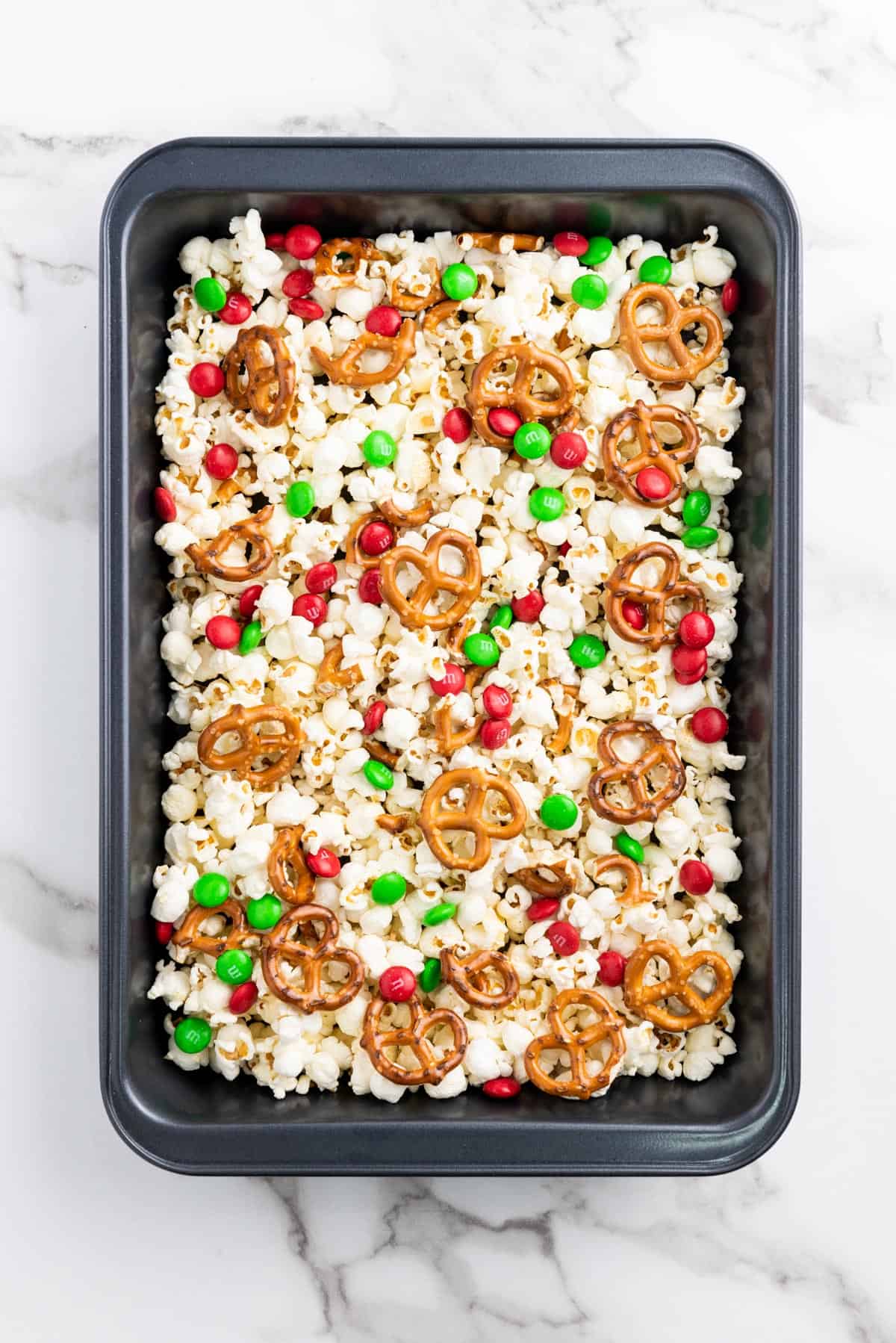Popcorn, pretzels, and M&Ms on a black tray.