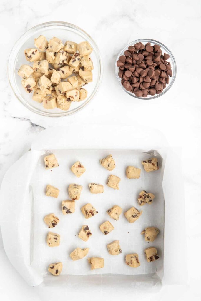 Chunks of cookie dough scattered in a square pan.