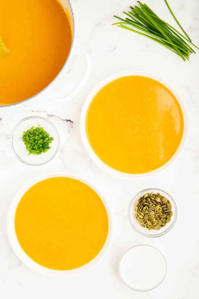 An overhead shot of two bowls of pumpkin soup without cream.