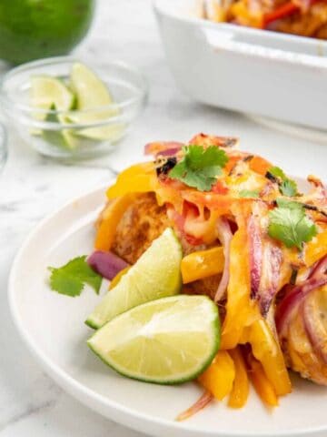 A close up shot of chicken fajita casserole served with lime wedges.