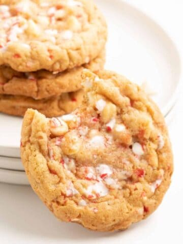 A close up of a white chocolate candy cane cookie with a bite taken out.